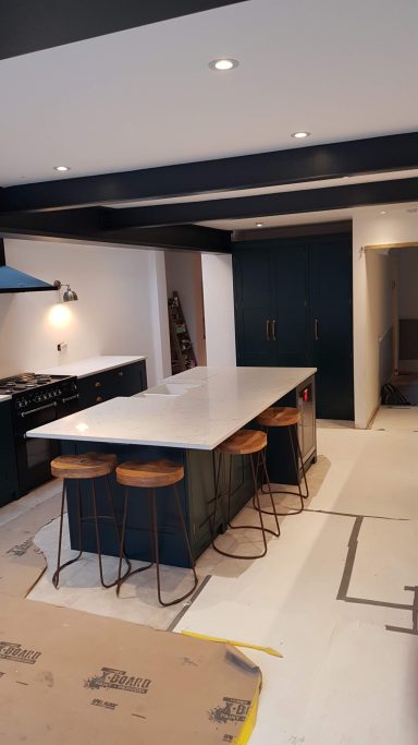 Modern kitchen with a large island, bar stools, and dark cabinetry.